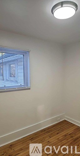 A room with wooden flooring and a window with blinds.