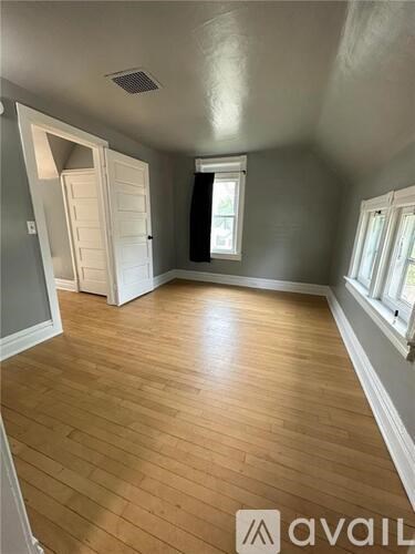 A room with wooden flooring and a doorway leading to another room.