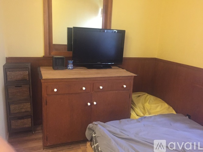 A bedroom with a bed, dresser, and a television.
