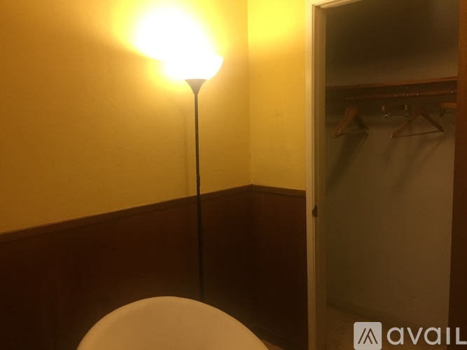 A lamp with a white shade is on in a room.