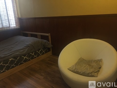 A bedroom with a bed and a chair.