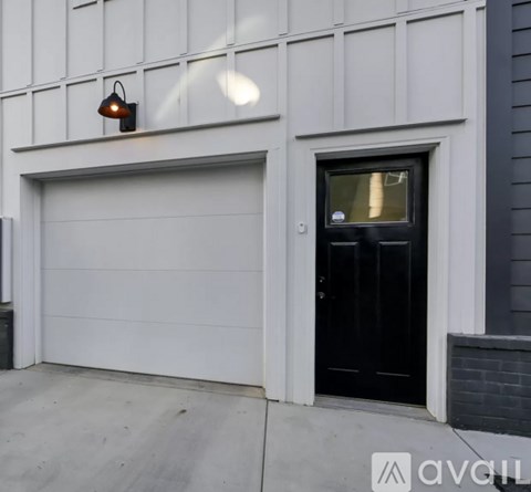 A black door is on the right side of a white garage door.