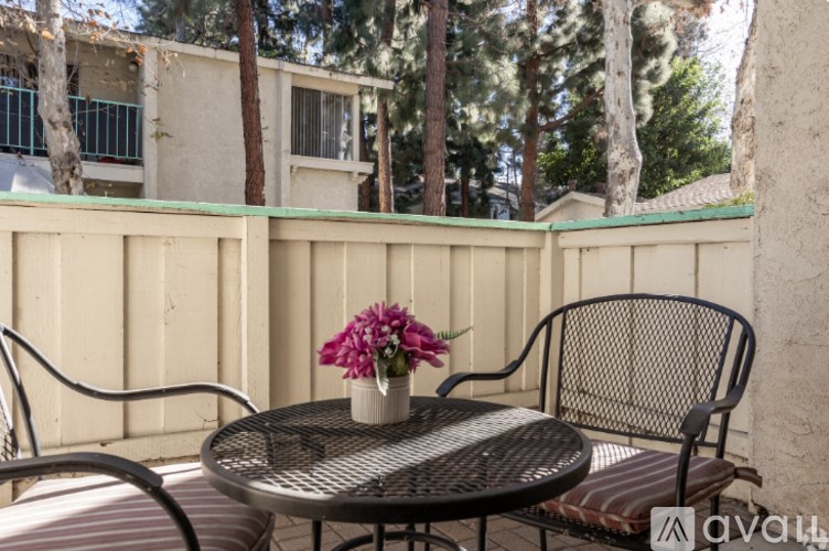 A patio with a table, chairs, and flowers.