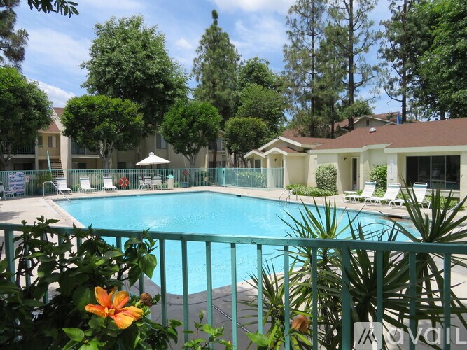 A pool surrounded by trees and a green fence.