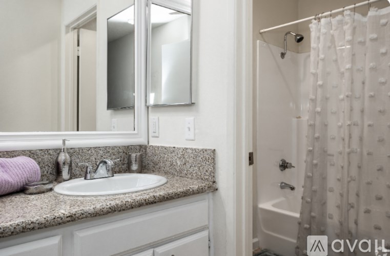 A bathroom with a sink, mirror, and shower.