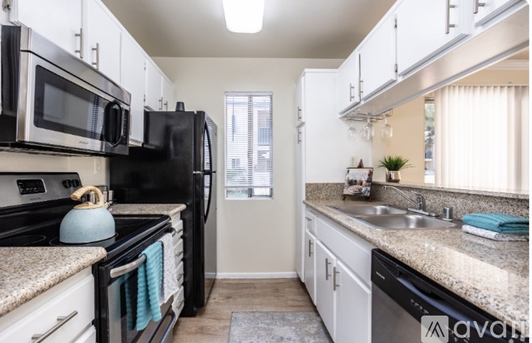 A kitchen with black appliances and white cabinets.