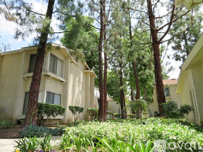 A row of houses with trees in front.