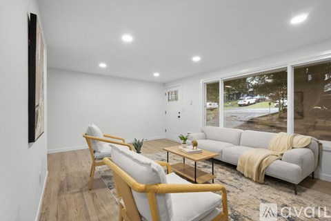 A living room with a white couch, a wooden coffee table, and a painting on the wall.