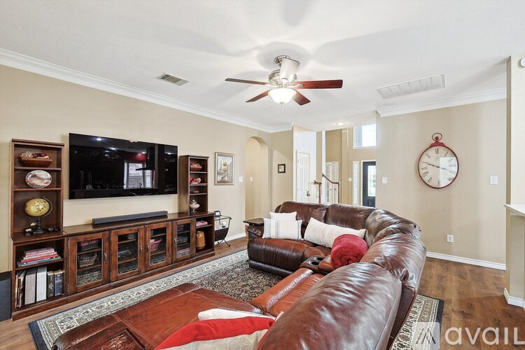 A living room with a brown leather couch and a flat screen TV mounted on the wall.