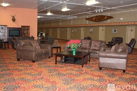 A living room with a brown leather couch, a coffee table, and a vase of flowers.