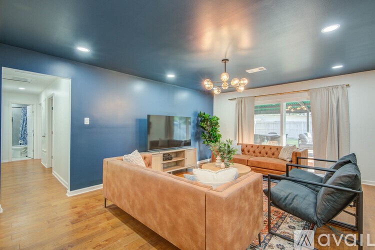 A living room with a brown couch, a television, and a plant.