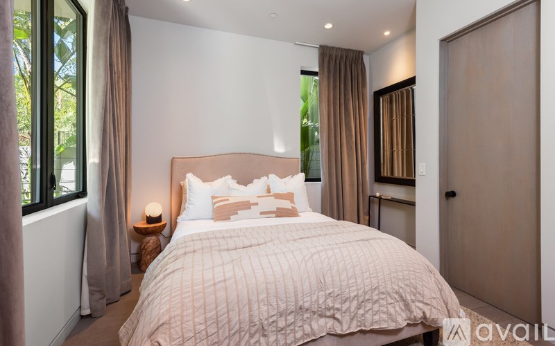 A bedroom with a large bed and a window with curtains.