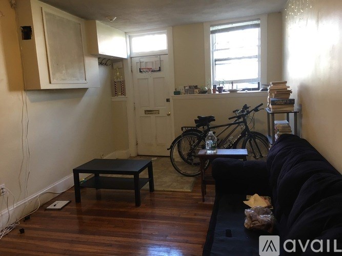 A living room with a black couch, a bicycle, and a window.