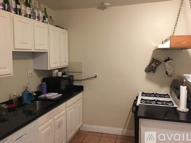 A kitchen with white cabinets and a black counter top.