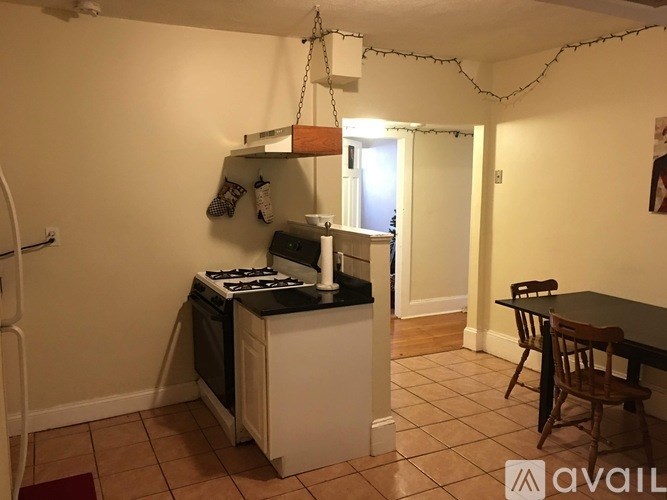 A kitchen with a stove and a hanging light fixture.