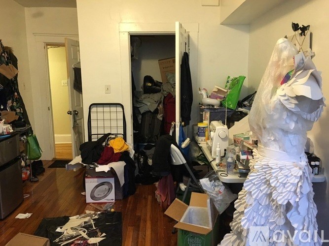 A messy room with a large sculpture of a woman in the corner.