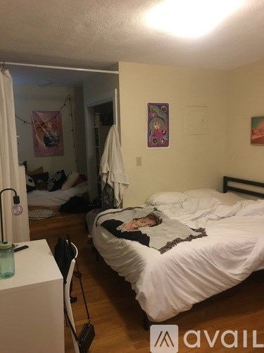 A person is lying on a bed in a room with a white bedspread.