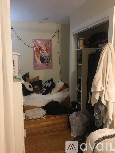 A room with a bed, a couch, and a poster on the wall.