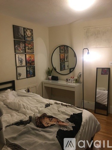 A person is lying on a bed in a room with a mirror and pictures on the wall.