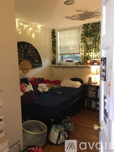 A bedroom with a bed, a window, and a wall hanging.