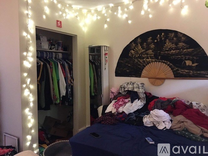 A bedroom with a bed, a wardrobe, and a wall hanging.