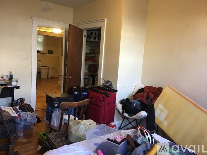 A messy room with a bed, chair, and various items scattered about.