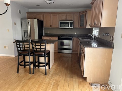 A kitchen with wooden floors and a black counter top.