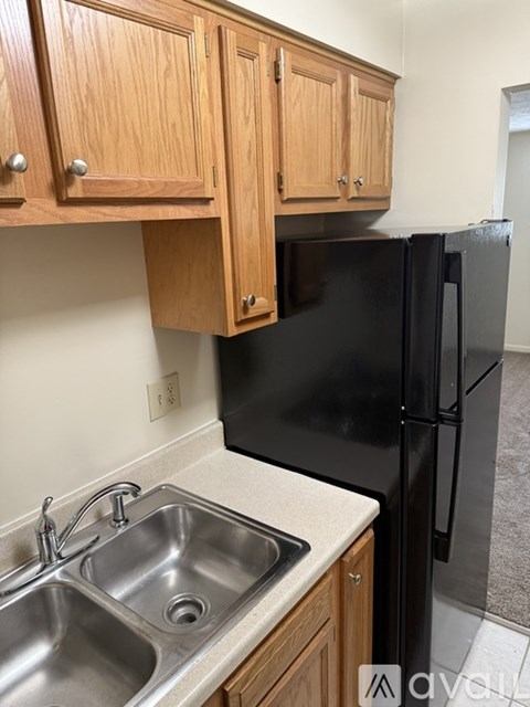 A kitchen with a black refrigerator and wooden cabinets.