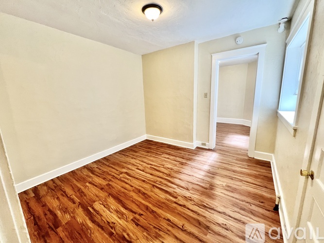 A room with wooden flooring and white walls.