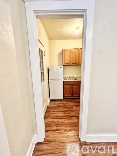 A kitchen with wooden cabinets and a white fridge is visible through an open door.