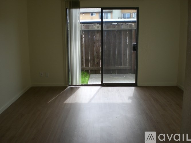A room with wooden flooring and a sliding glass door leading to a backyard.