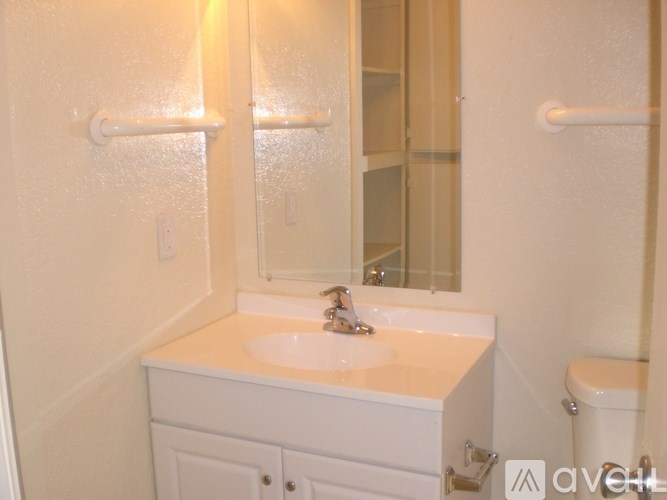 A white bathroom with a sink, toilet, and mirror.