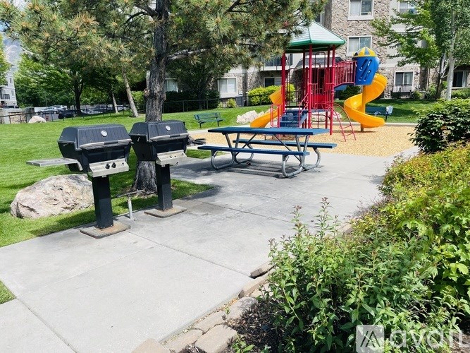 A playground with a slide, picnic table, and trash cans.