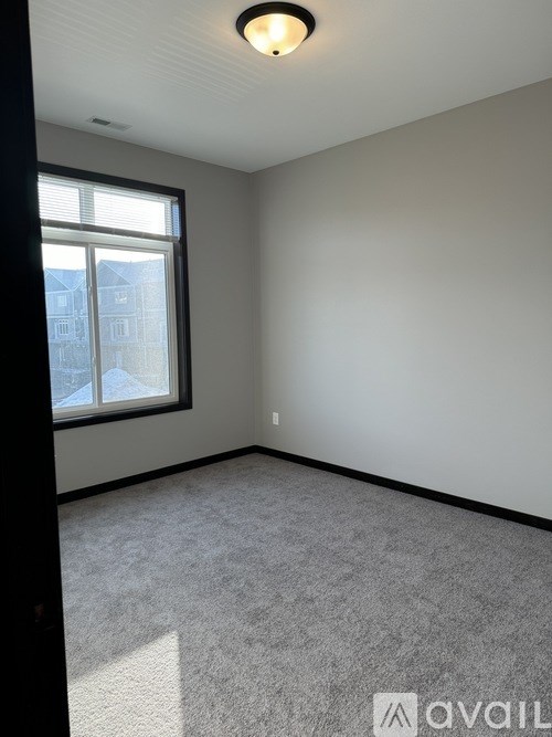 A room with a window and a carpeted floor.