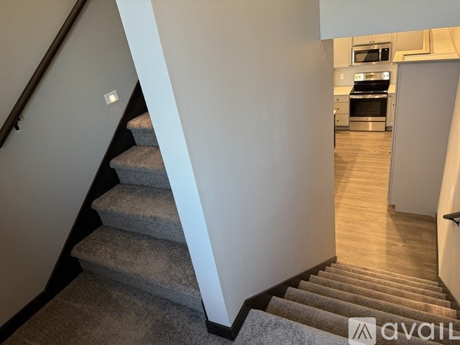 A staircase with a carpeted runner leads to a kitchen area.