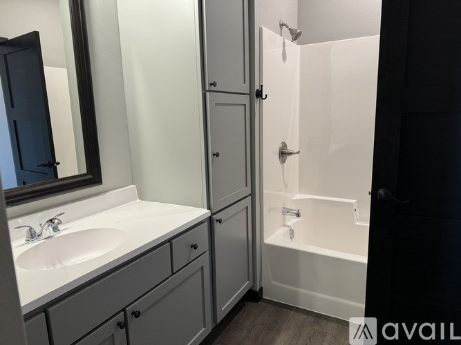 A bathroom with a sink, mirror, and shower.