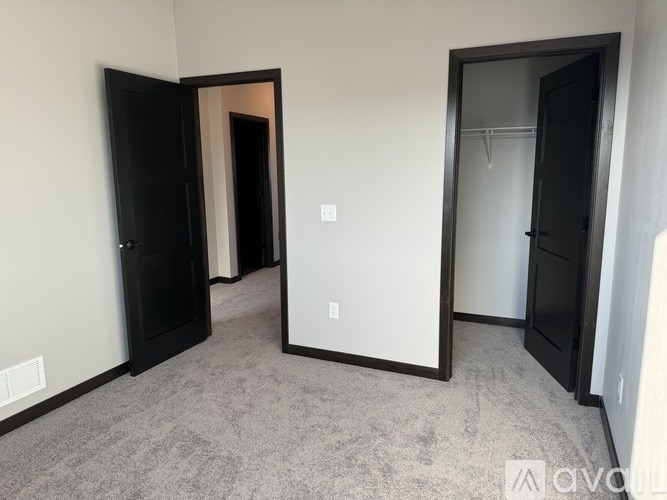 A room with a carpeted floor and two open doors.