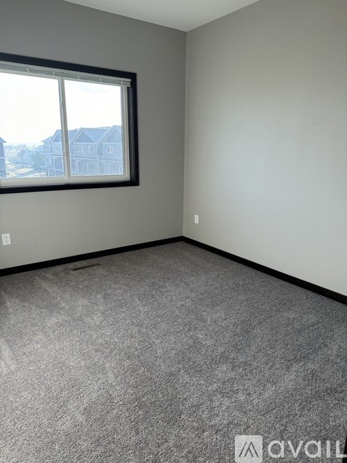 A room with a carpeted floor and a window showing a view of a house.