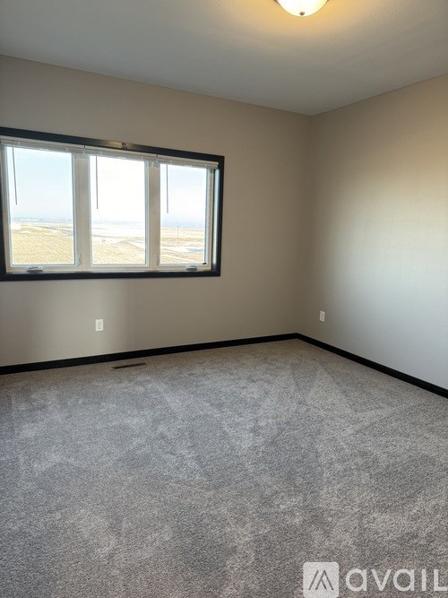 A room with a carpeted floor and a window overlooking the beach.