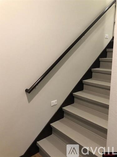 A staircase with a black handrail and white steps.