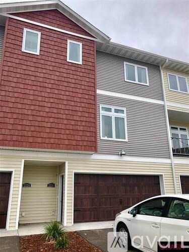 A white car is parked in front of a two-story building.