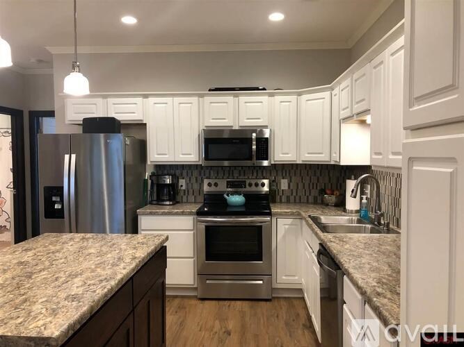 A kitchen with white cabinets and a granite countertop.