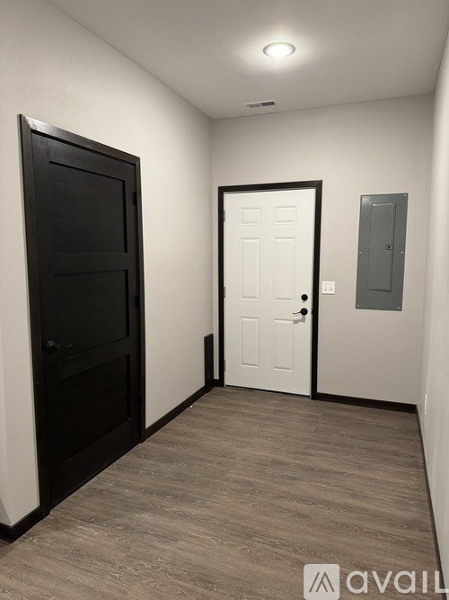 A hallway with a black door on the left and a white door on the right.