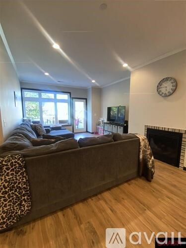 A living room with a grey couch and a leopard print throw.