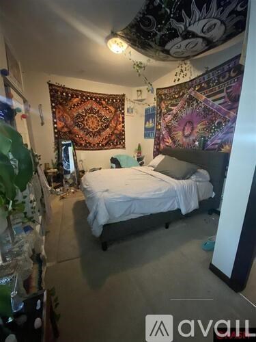 A bedroom with a bed, a wall hanging, and a rug.