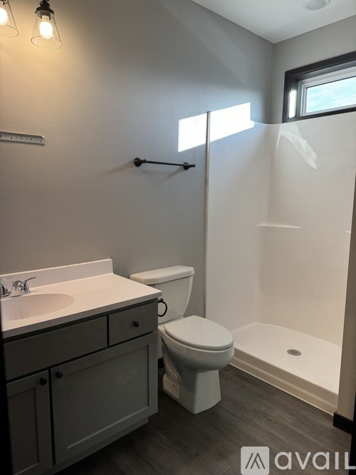 A bathroom with a toilet, sink, and shower.