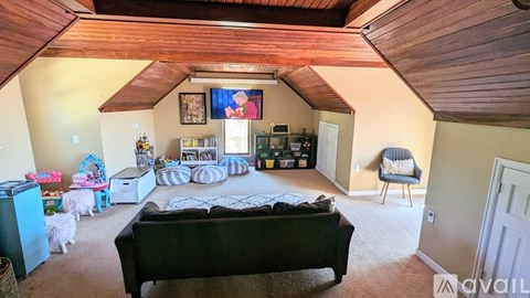 A living room with a black couch and a television on the wall.