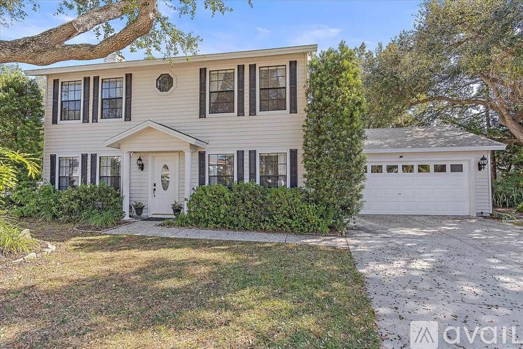 A two-story house with a white garage door and a driveway.