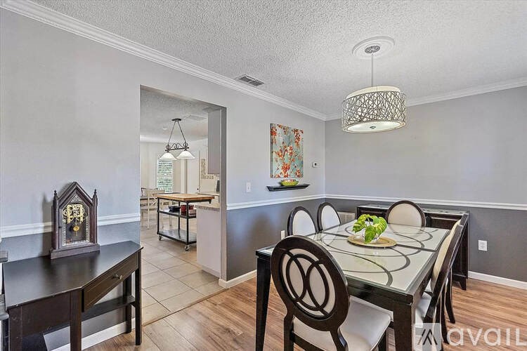 A dining room with a table set for two and a chandelier hanging from the ceiling.