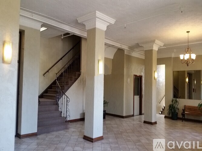 A spacious hallway with a staircase and a chandelier.